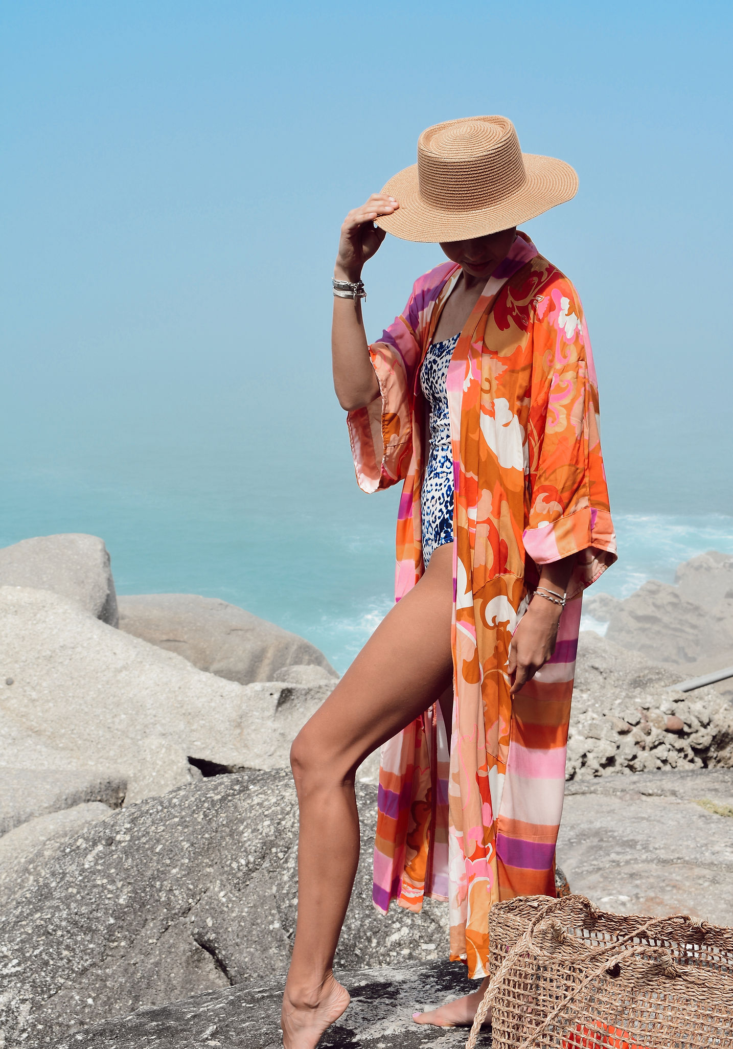 Woman wearing a vibrant orange kaftan on the rocky Cape coastline